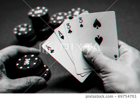 Playing poker in the casino. Cards with two pairs in the hand of the player making a bet with chips 69754701