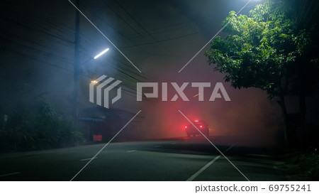 Pickup truck drive into fog on empty road with red taillight in silent town Pickup truck drive into fog on empty road with red taillight in silent town 69755241
