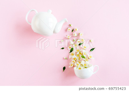 Creative layout of teapot and tea Cup with Jasmine flowers on a pink background. Jasmine tea. 69755423