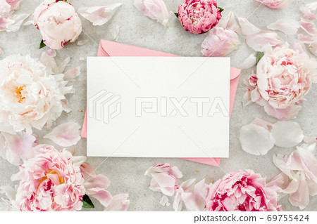 Mockup invitation, blank paper greeting card, pink envelope and peonies on gray stone table. Flower background. Flat lay, top view. Mockup invitation, blank paper greeting card, pink envelope and peonies on gray stone table. Flower background. Flat lay, top view. 69755424