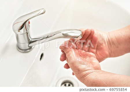 Senior elderly woman wash hands under tap water Senior elderly woman wash hands under tap water 69755854