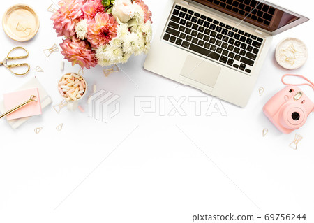 Stylized women's home office desk. Workspace with laptop, computer, bouquet ranunculus and roses, clipboard on white background. Flat lay. Top view. Stylized women's home office desk. Workspace with laptop, computer, bouquet ranunculus and roses, clipboard on white background. Flat lay. Top view. 69756244