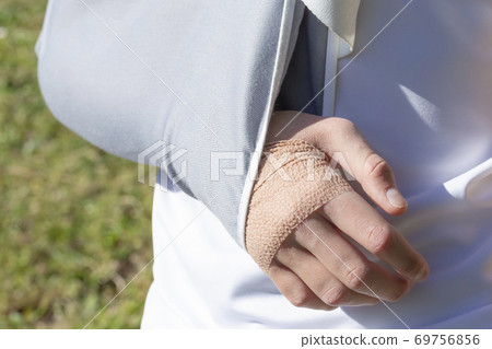 A boy with an injured hand in a fixing bandage on the background of a football field, meadows A boy with an injured hand in a fixing bandage on the background of a football field, meadows 69756856