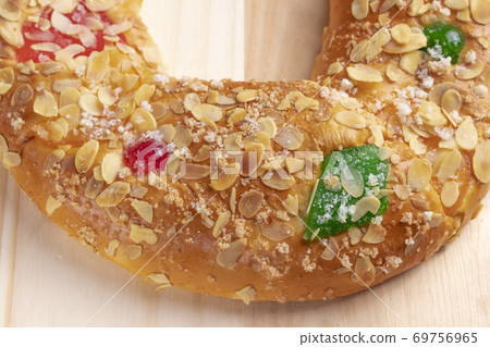 Spanish typical Epiphany cake Roscon de Reyes with fruit on a wooden background Spanish typical Epiphany cake Roscon de Reyes with fruit on a wooden background 69756965
