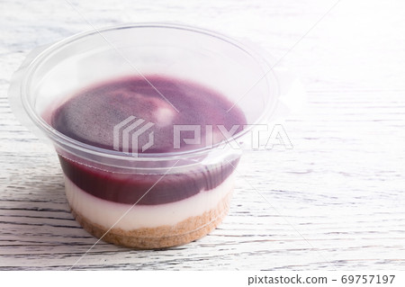 Tiramisu with blueberry mousse in a closed plastic jar on a white wooden table. Close-up 69757197