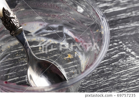 empty plastic packaging with a spoon, leftovers eaten by teramis on a dark wooden background empty plastic packaging with a spoon, leftovers eaten by teramis on a dark wooden background 69757235