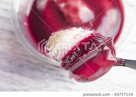 Tiramisu with the addition of blueberries in a plastic jar. Broke a piece of dessert spoon. Close-up Tiramisu with the addition of blueberries in a plastic jar. Broke a piece of dessert spoon. Close-up 69757239