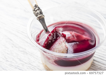 Tiramisu with the addition of blueberries in a plastic jar. Broke a piece of dessert spoon. Close-up Tiramisu with the addition of blueberries in a plastic jar. Broke a piece of dessert spoon. Close-up 69757327