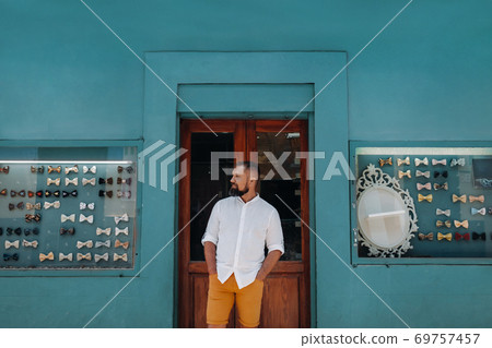 A man in the Old town of La Laguna on the island of Tenerife on a Sunny day against the background of a counter with butterflies on costumes.Butterflies for men's costumes in the Canary Islands.Spain. 69757457