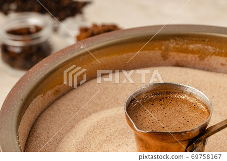 Copper turk with coffee brewing in sand 69758167