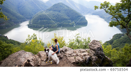 woman and dog on mountain top above lake 69758504