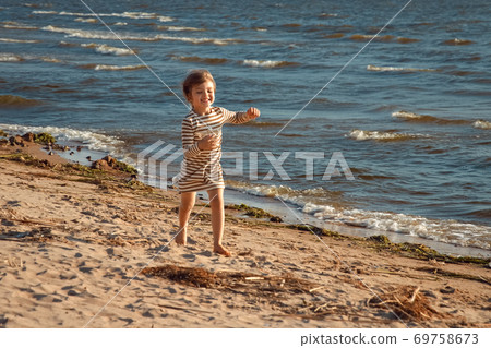 happy child girl running along the shore of the baltic sea beach happy child girl running along the shore of the baltic sea beach 69758673