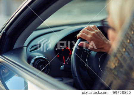 Close up rear view of a woman driving car through the city 69758890