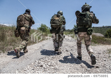 Army soldiers running on road in abandoned area 69758891