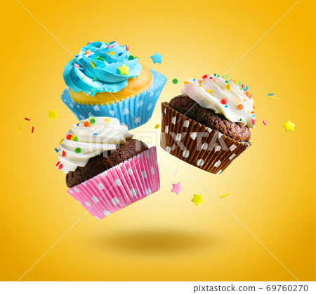 Cupcakes flying over yellow background. Cupcakes flying over yellow background. 69760270