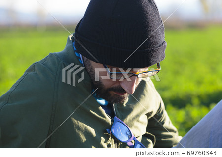 Close-up portrait of a young adult man looking down in a meadow. Close-up portrait of a young adult man looking down in a meadow. 69760343
