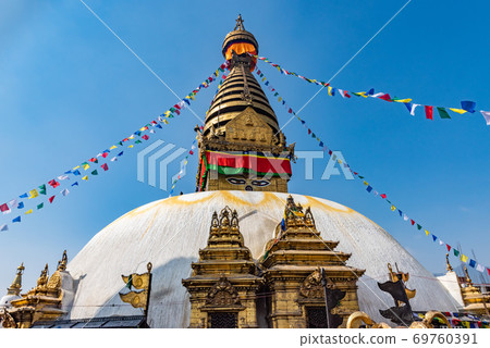 Tower of the Boudhanath Stupa decorated with flags in Kathmandu, Nepal. 69760391