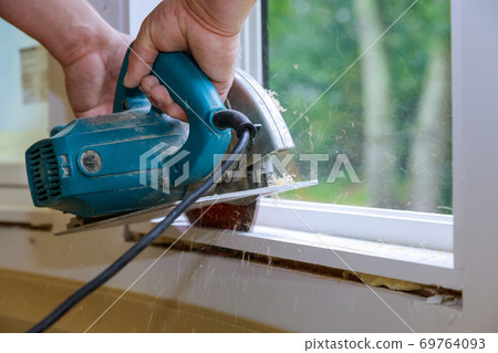 Carpenters hands cutting wood with electric saw 69764093