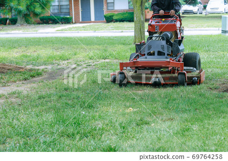 Close up of man using a lawn mower a gardener cutting grass by lawn mower Close up of man using a lawn mower a gardener cutting grass by lawn mower 69764258