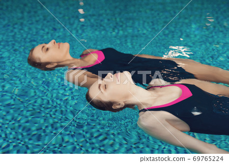 Girls in swimsuits lie on their backs and swim. Girls in swimsuits lie on their backs and swim. 69765224