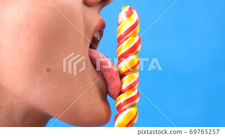 sexy brunette woman with lollipop isolated on a blue background. 69765257