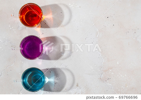Glasses with colored liquid on a light marble background Glasses with colored liquid on a light marble background 69766696
