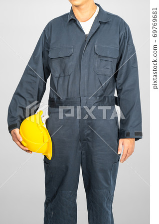 Worker standing in blue coverall holding hardhat Worker standing in blue coverall holding hardhat 69769681