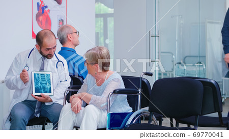 Physician giving diagnosis on X ray tablet PC Physician giving diagnosis on X ray tablet PC 69770041