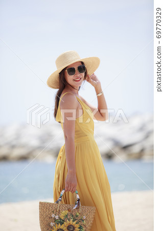 beautiful woman wearing yellow dress standing with happiness smiling at sea side beautiful woman wearing yellow dress standing with happiness smiling at sea side 69770329