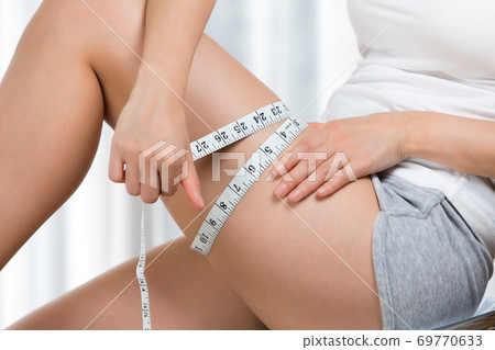 A woman who measures her thighs with a major. A woman who measures her thighs with a major. 69770633