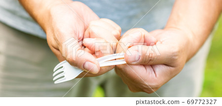 Male hand breaks plastic disposable fork Male hand breaks plastic disposable fork 69772327
