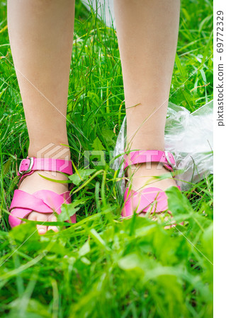Plastic bags trash with children's feet on green grass Plastic bags trash with children's feet on green grass 69772329