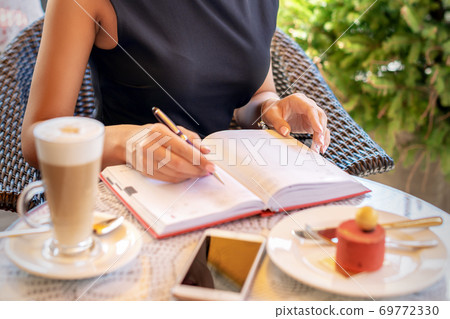 Business woman in black dress writes in notebook 69772330