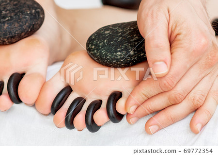 Hot little black stones between female toes 69772354