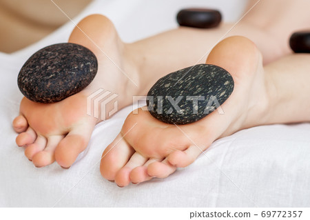 Hot stones lying on female feet Hot stones lying on female feet 69772357