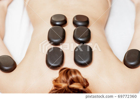 Black hot stones lying on female back Black hot stones lying on female back 69772360