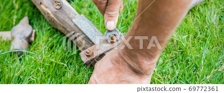 Elderly man twists the nut by wrench Elderly man twists the nut by wrench 69772361