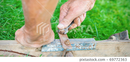 Elderly man twists the nut by wrench Elderly man twists the nut by wrench 69772363