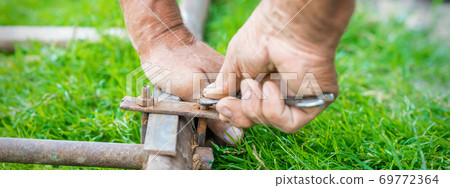 Elderly man twists the nut by wrench Elderly man twists the nut by wrench 69772364