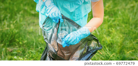 Child picks plastic trash from grass Child picks plastic trash from grass 69772479
