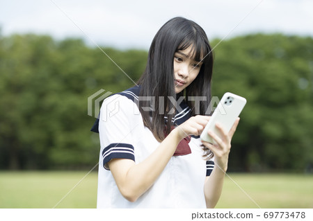 High school girl operating a smartphone High school girl operating a smartphone 69773478
