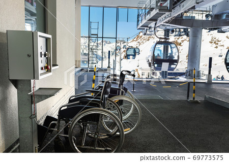 Many empty wheelchairs prepared for disabled people at station of cabin gondola ski lift at mountain alpine luxury austrian winter resort. Handicapped person friendly care service Many empty wheelchairs prepared for disabled people at station of cabin gondola ski lift at mountain alpine luxury austrian winter resort. Handicapped person friendly care service 69773575