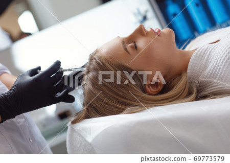Doctor cosmetologist making mesotherapy injections in woman's head Doctor cosmetologist making mesotherapy injections in woman's head 69773579