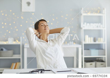 Relaxed woman in her home office enjoying great sense of achievement after finishing all daily tasks 69774104