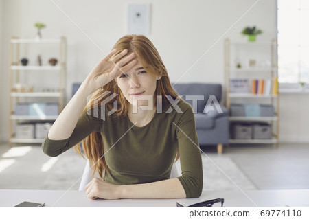 Stressed tired woman looking at camera during online lesson or meeting and expressing headache Stressed tired woman looking at camera during online lesson or meeting and expressing headache 69774110