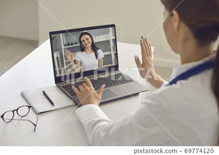 Woman patient greeting her doctor online from laptop screen during videocall on laptop Woman patient greeting her doctor online from laptop screen during videocall on laptop 69774120