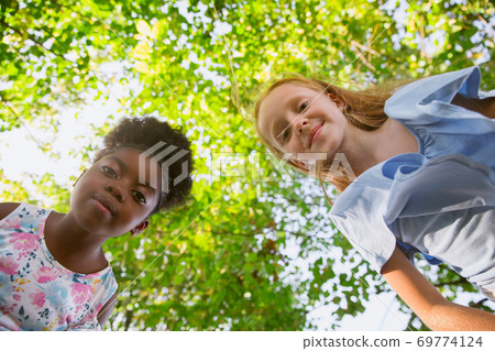 Interracial kids, friends, girls playing together at the park in summer day Interracial kids, friends, girls playing together at the park in summer day 69774124