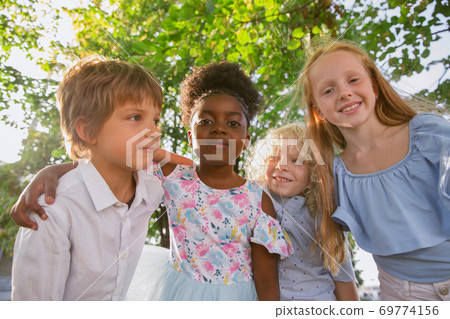 Interracial group of kids, girls and boys playing together at the park in summer day 69774156
