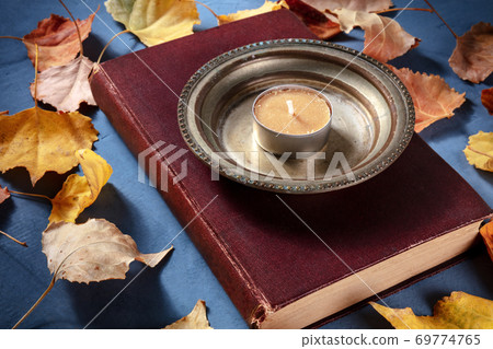 Fall reading concept, and old book with a candle and autumn leaves Fall reading concept, and old book with a candle and autumn leaves 69774765