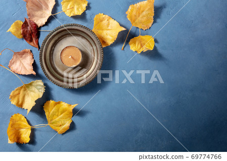 Autumn background with yellow leaves and a candle, with copy space, a flat lay Autumn background with yellow leaves and a candle, with copy space, a flat lay 69774766